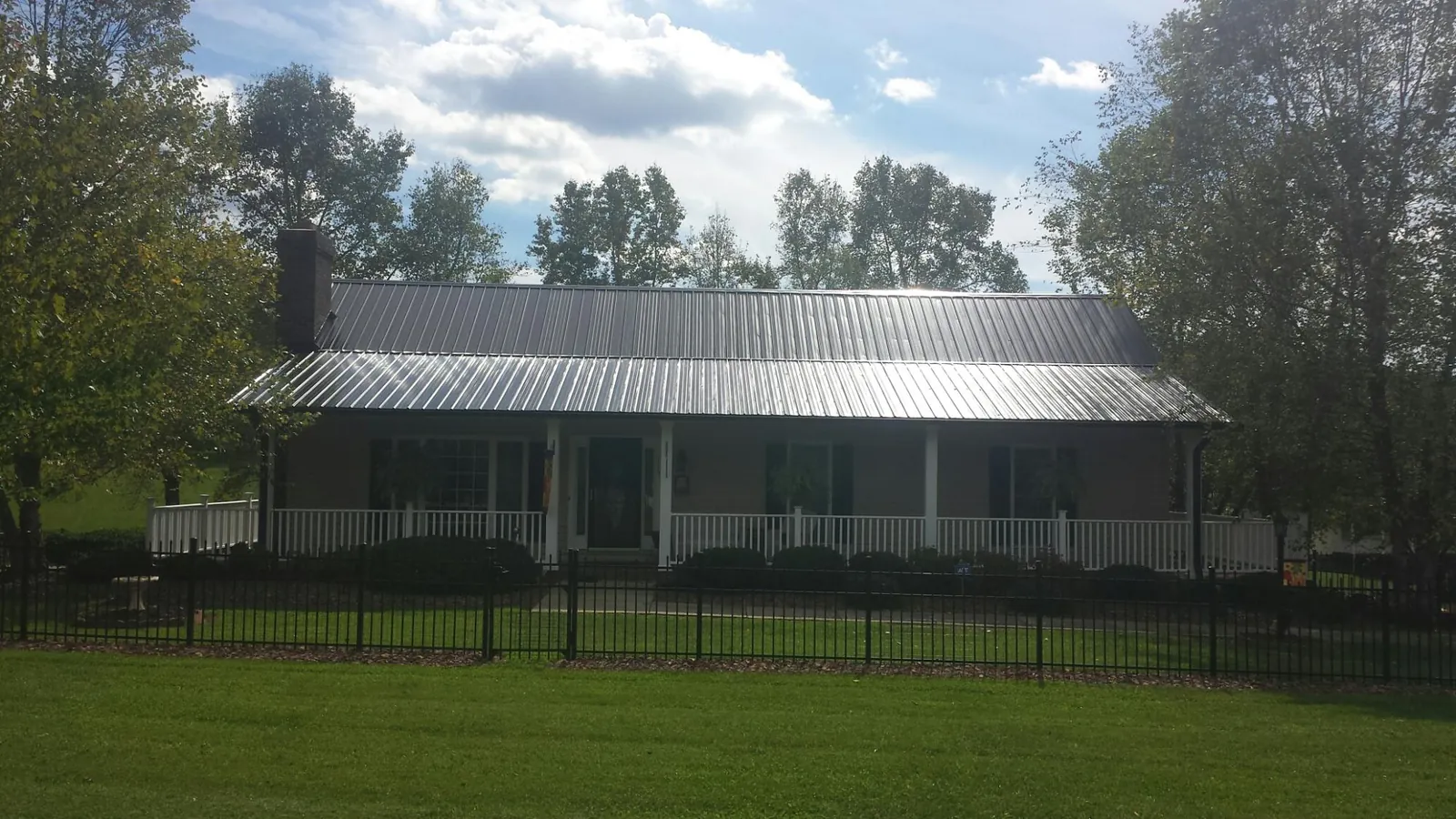 Gray metal roof on a brick ranch with a full width front porch — Gutter Guard Installation work by our crew in Aurora