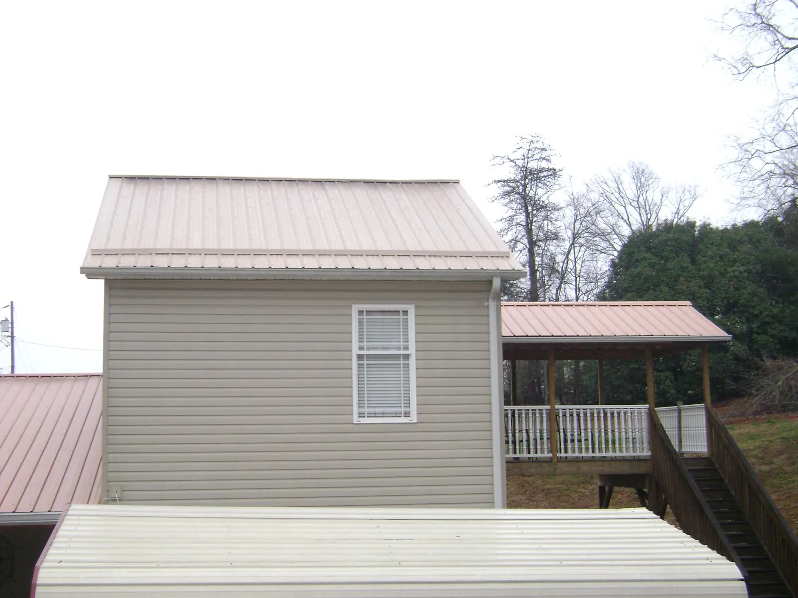 Tan metal roofs on a two story addition and attached porch, from a Roof Replacement job in Aurora